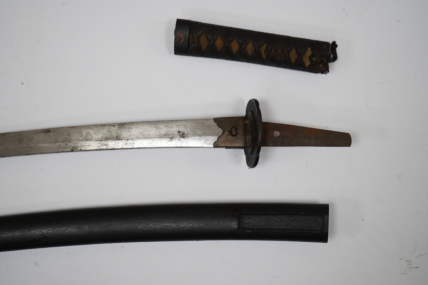 A Japanese short sword wakizashi, blade 42.5cm unsigned, iron mokko tsuba with inlaid details, tape bound same tsuka, with iron fuchi (kashira missing) in its black lacquered saya. Condition - poor to fair.